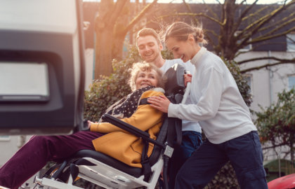 helpers picking up disabled senior woman for transport