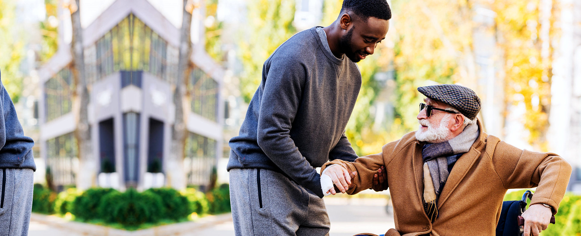 aide assisting elderly in wheelchair with standing up